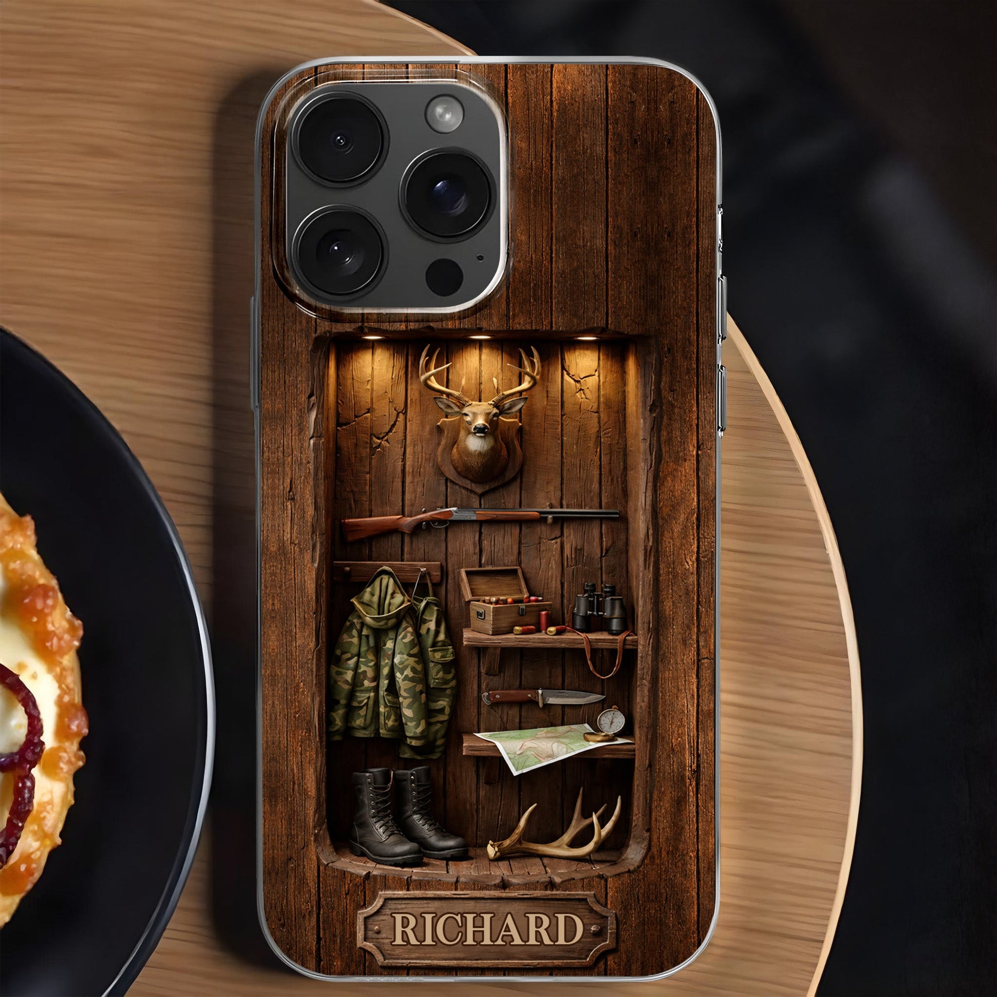 Custom hunting cabin phone case with rustic wood wall, mounted deer head, rifle, camo jacket, and personalized name plate