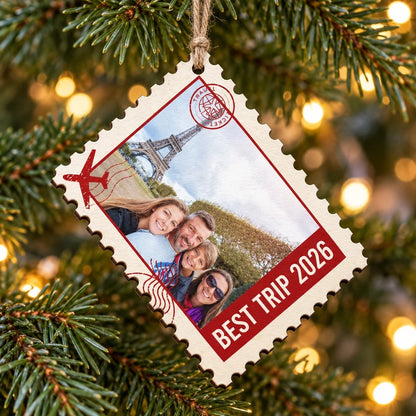 Custom photo postage stamp wood ornament BEST TRIP 2026 hanging on a bright Christmas tree branch