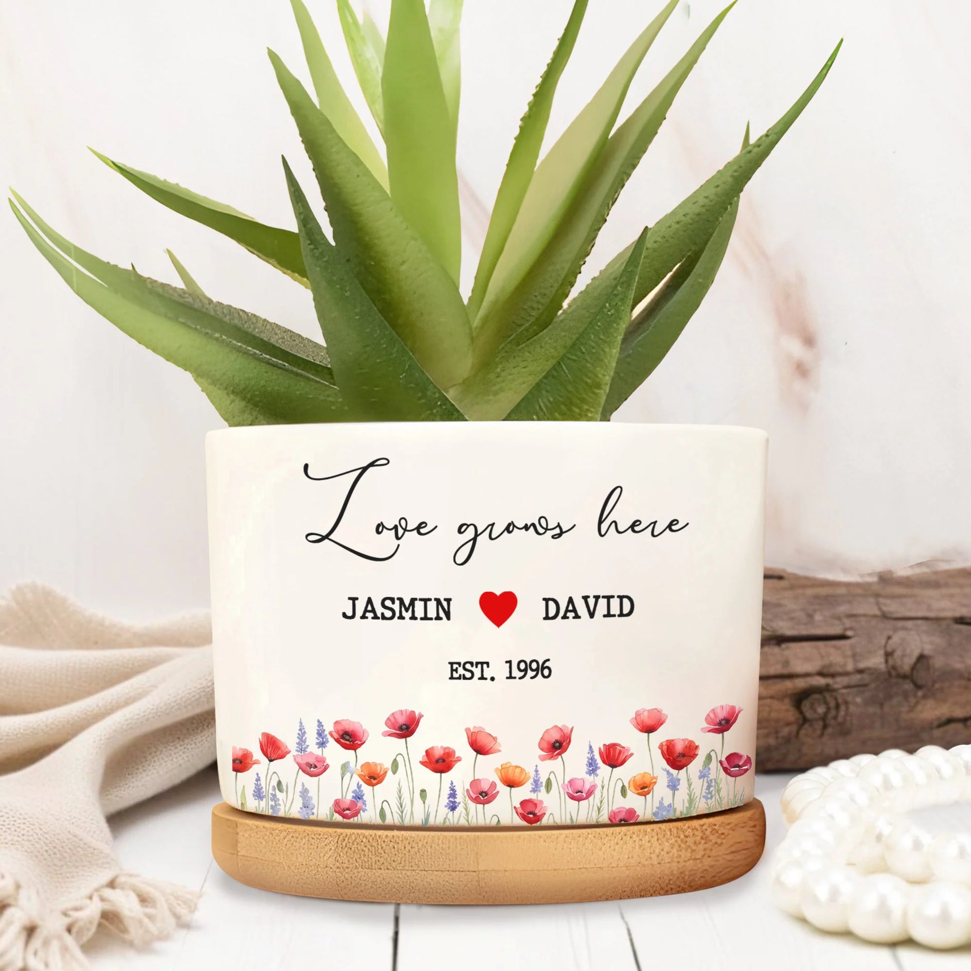 Personalized ceramic plant pot with "Love Grows Here" script design, custom names, and floral border illustration